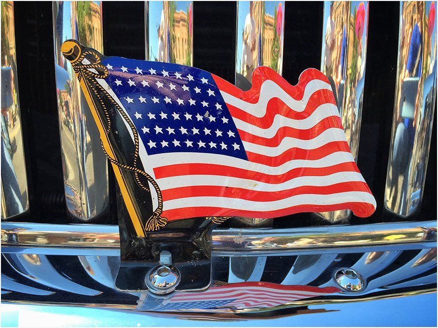 An american flag is on the grille of a car