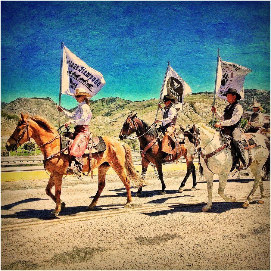 A group of people riding horses carrying flags one of which says wild west