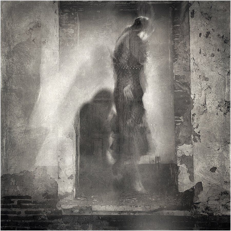 A black and white photo of a person standing in a doorway