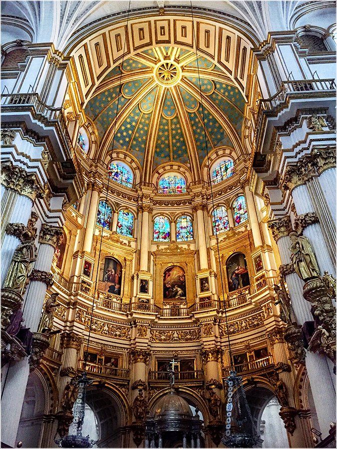 The inside of a church with a dome and stained glass windows.