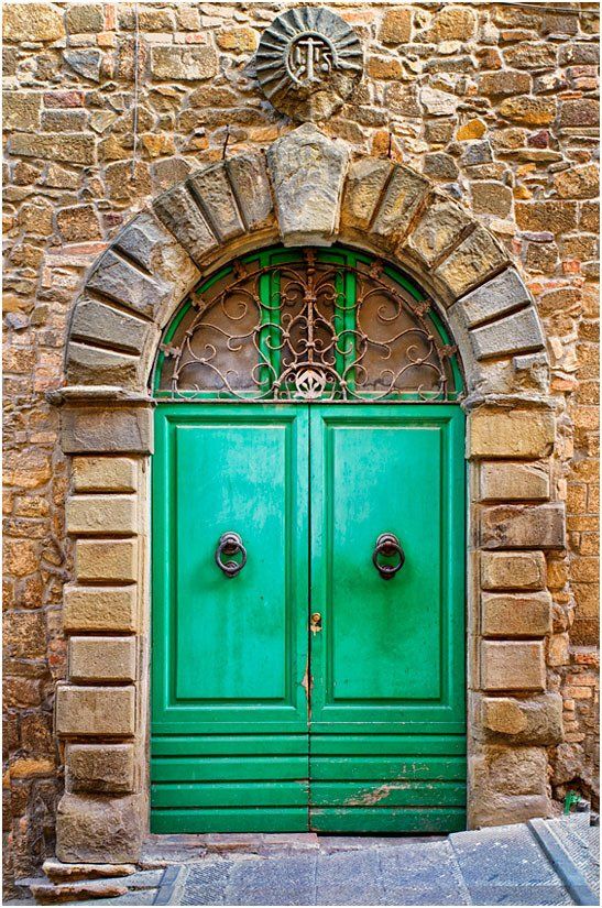 A green door is in the middle of a stone wall.