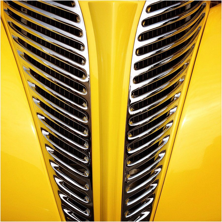 A close up of a yellow car with a chrome grille