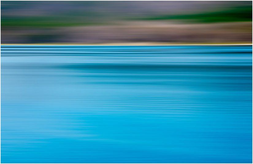 A blurry picture of a body of water with trees in the background.