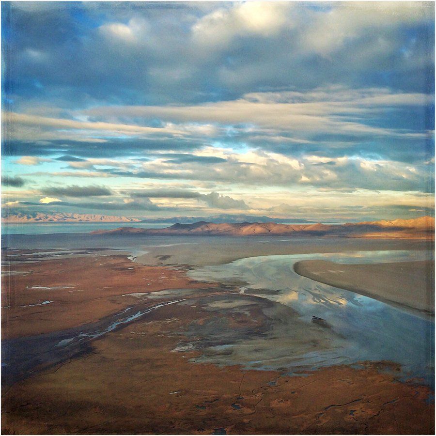 An aerial view of a river flowing through a desert landscape at sunset.