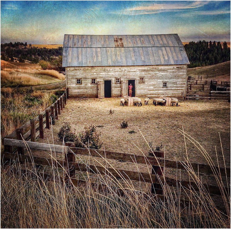 An old barn with a fence in front of it