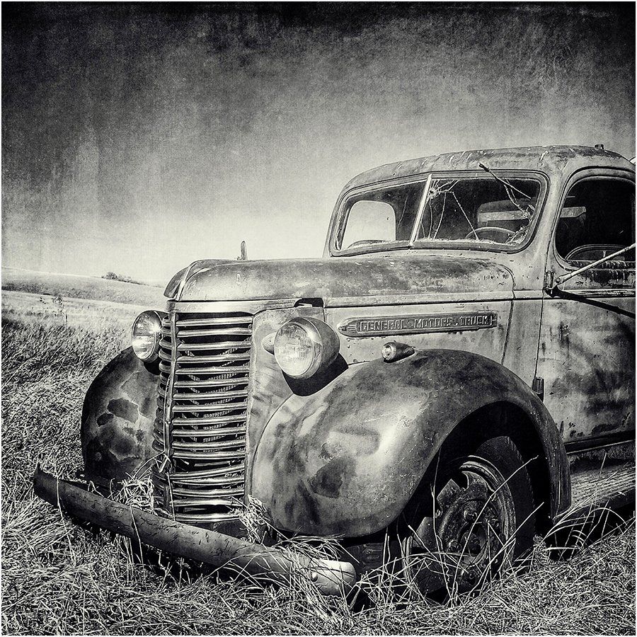 A black and white photo of an old rusty truck