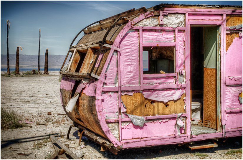 A pink trailer is sitting in the middle of a desert