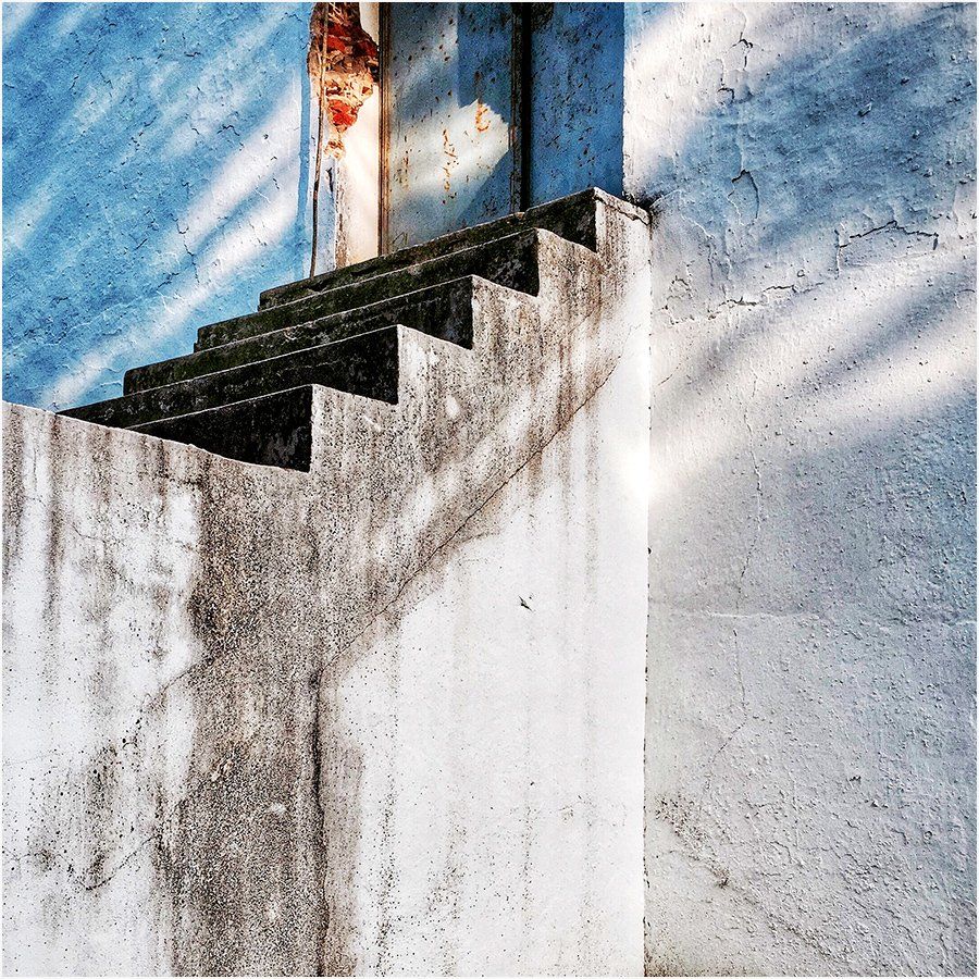 A set of stairs on a white wall with a blue sky in the background