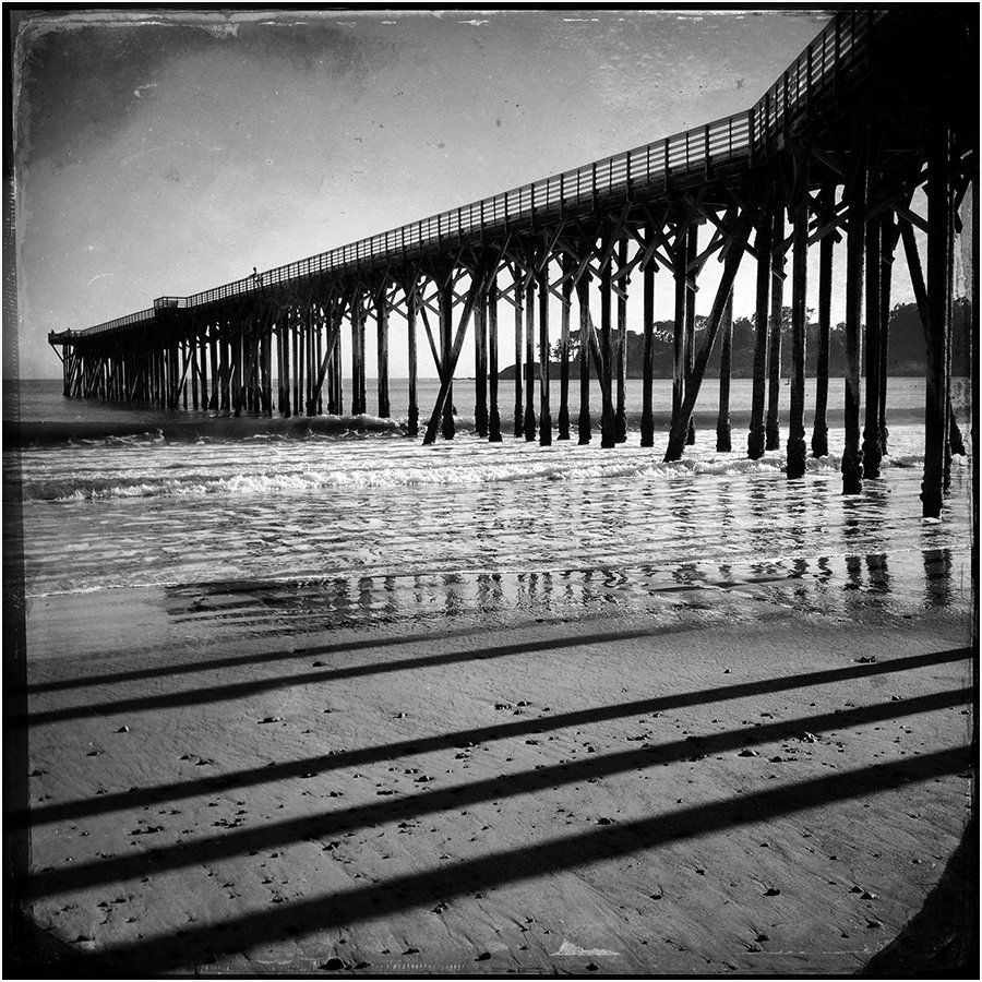 A black and white photo of a pier over a body of water