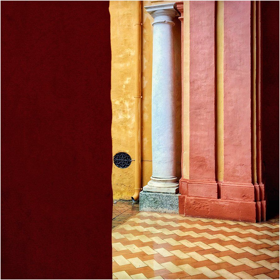 A corner of a building with columns and a red wall
