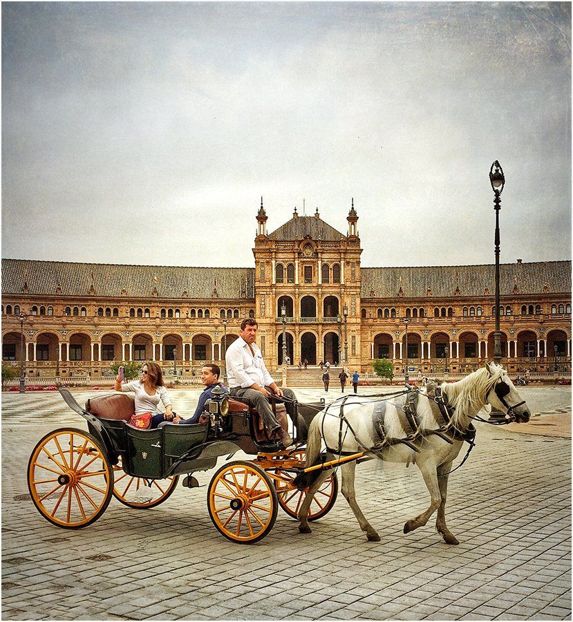 A horse drawn carriage with people in it in front of a building