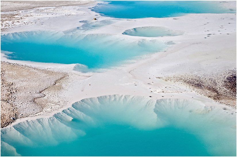 Aerial view of a lake filled with blue water and white sand.