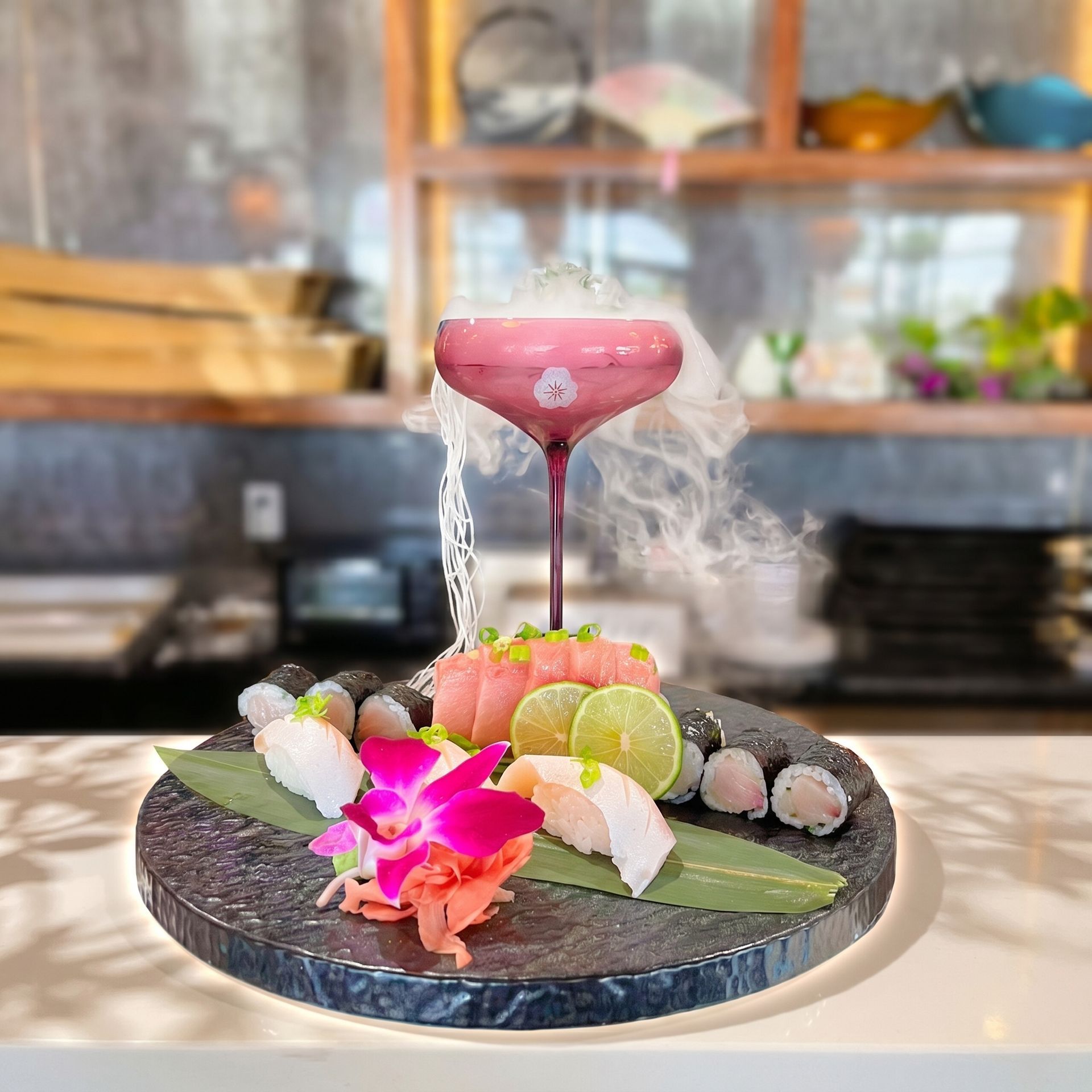 Sushi platter with a pink cocktail martini and rising steam on a dark plate