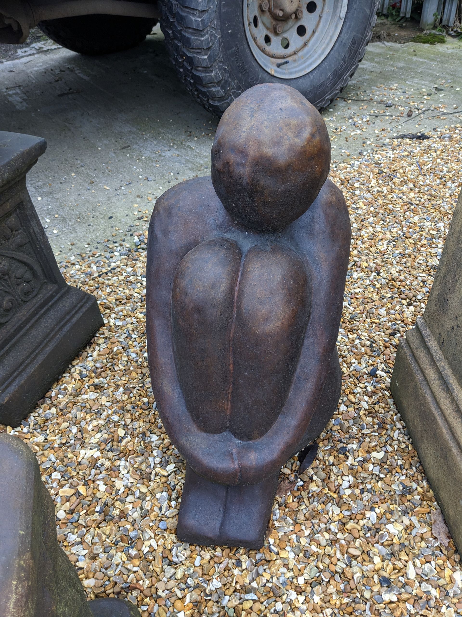 man male holding knees stone garden statue