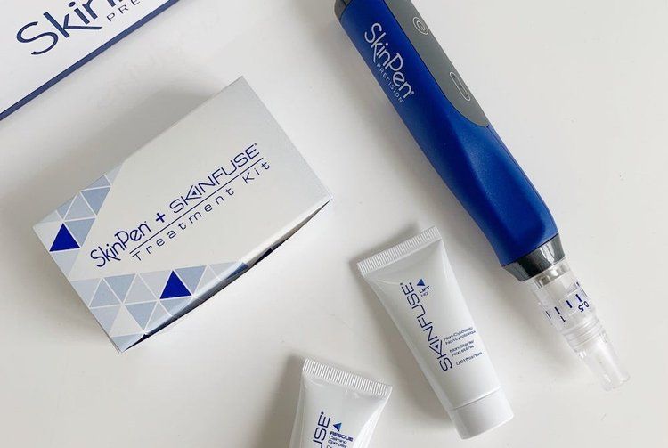 A blue skin pen is sitting next to a box of skin pen treatment kit.