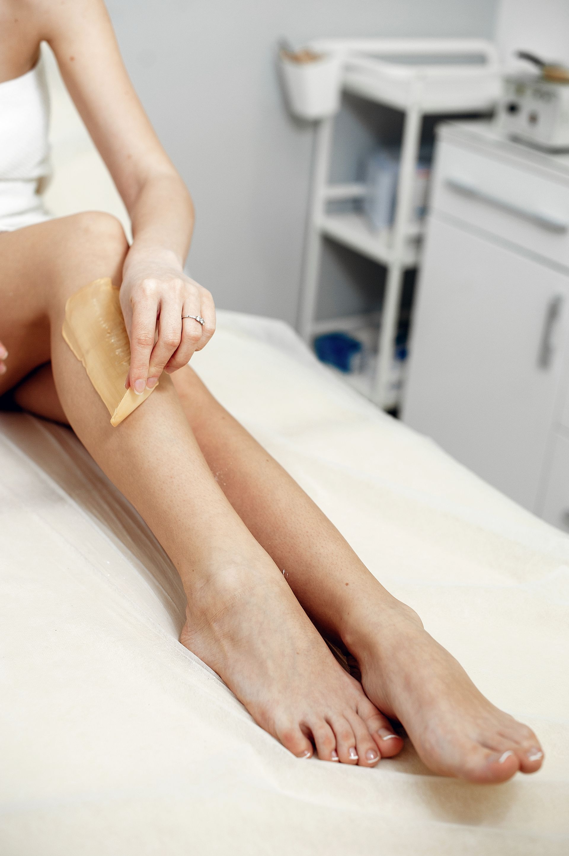 A woman is waxing her legs in a beauty salon.