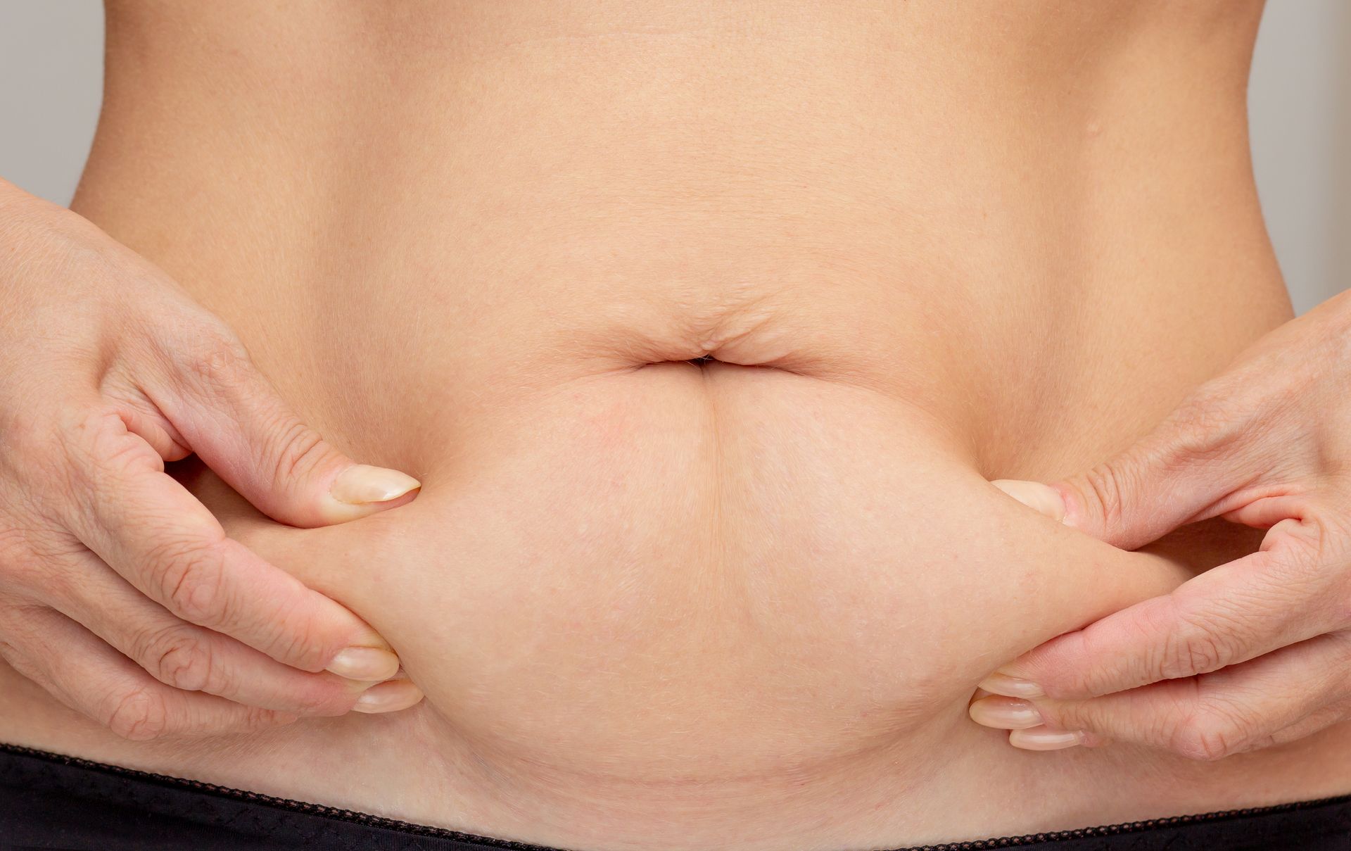 A woman is holding her stomach with her hands.