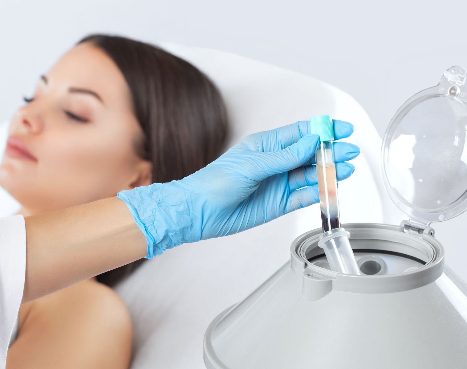 A woman is laying in a bed while a doctor is holding a test tube.