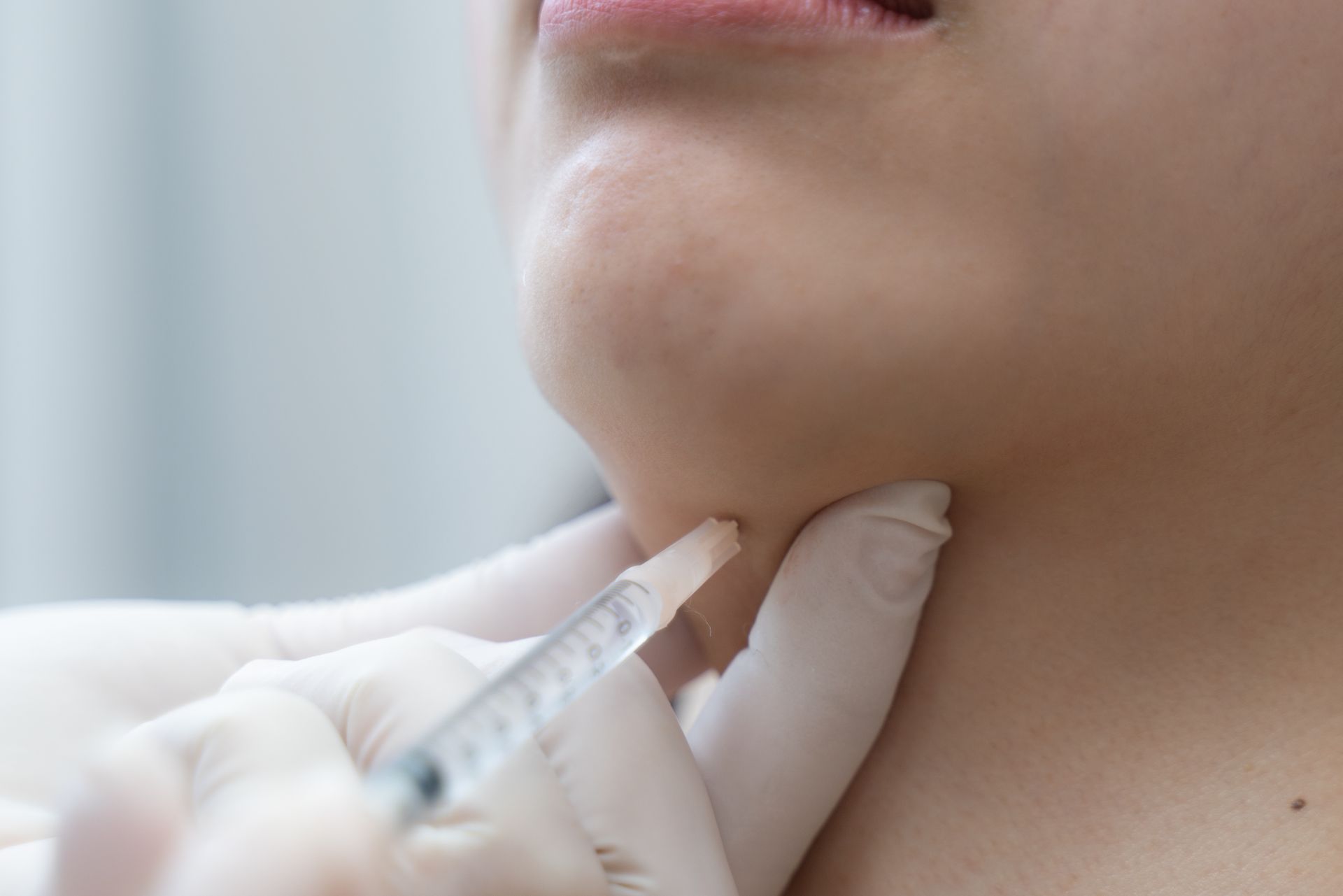 A woman is getting a kybella injection in her neck.