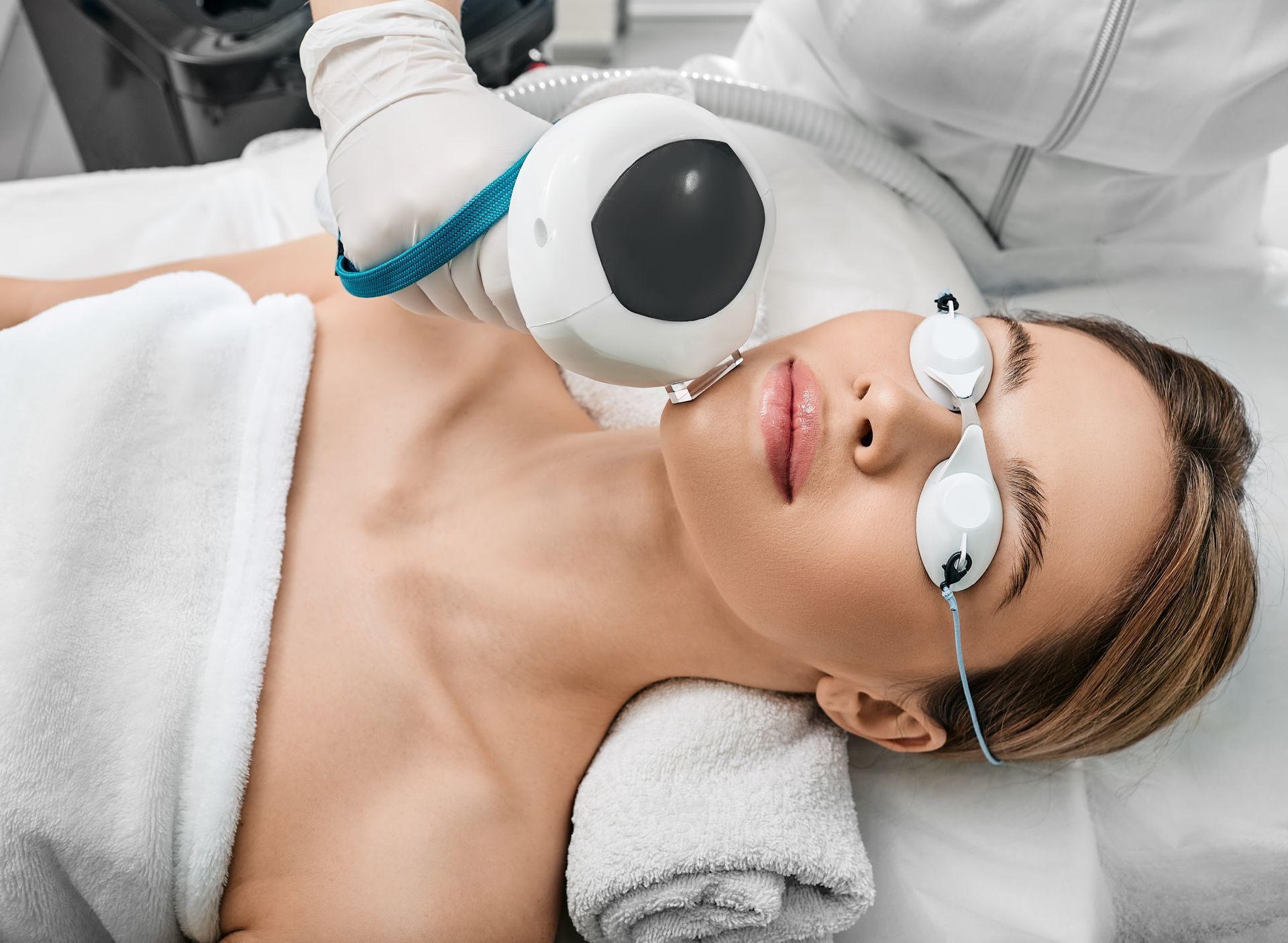 A woman is getting an IPL treatment on her face.