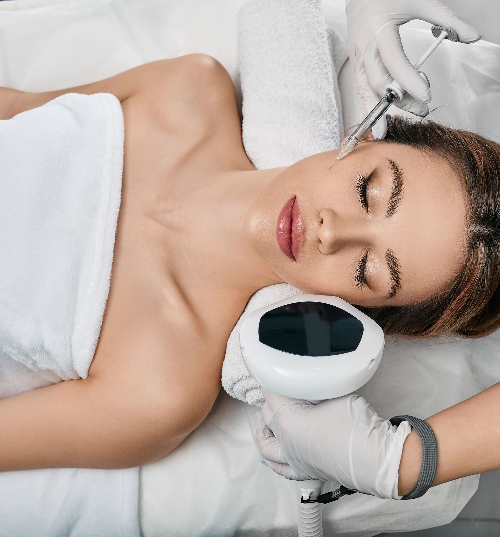 A woman is laying on a bed getting a facial treatment.