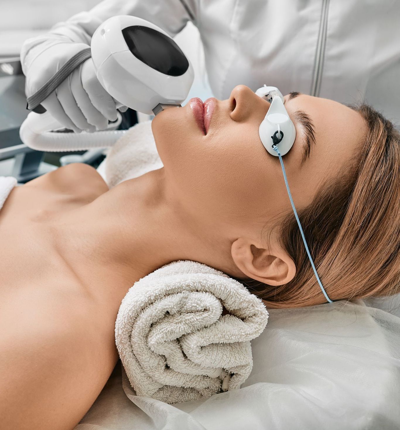 A woman is getting an IPL treatment on her face.