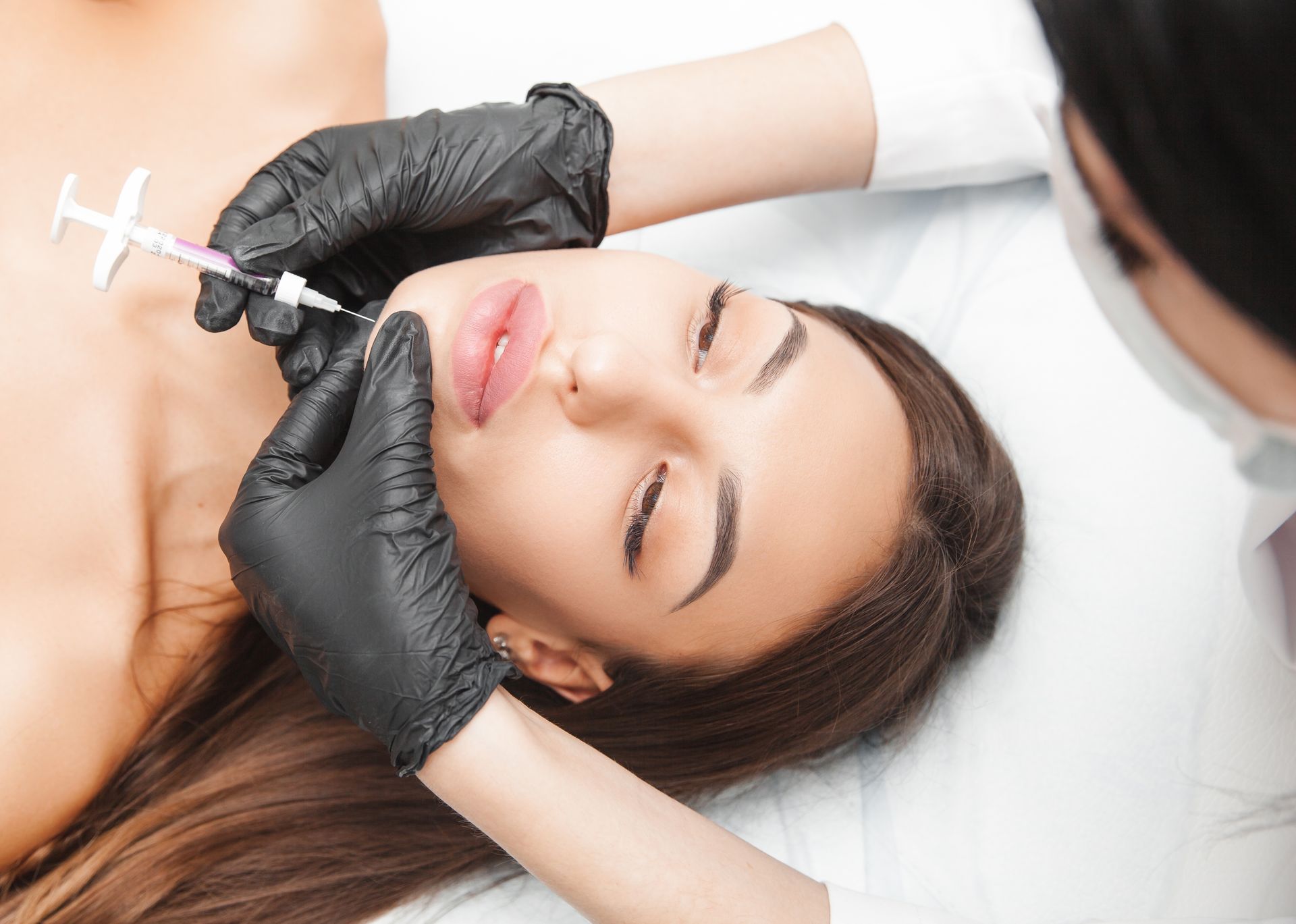 A woman is getting a kybella injection in her face.