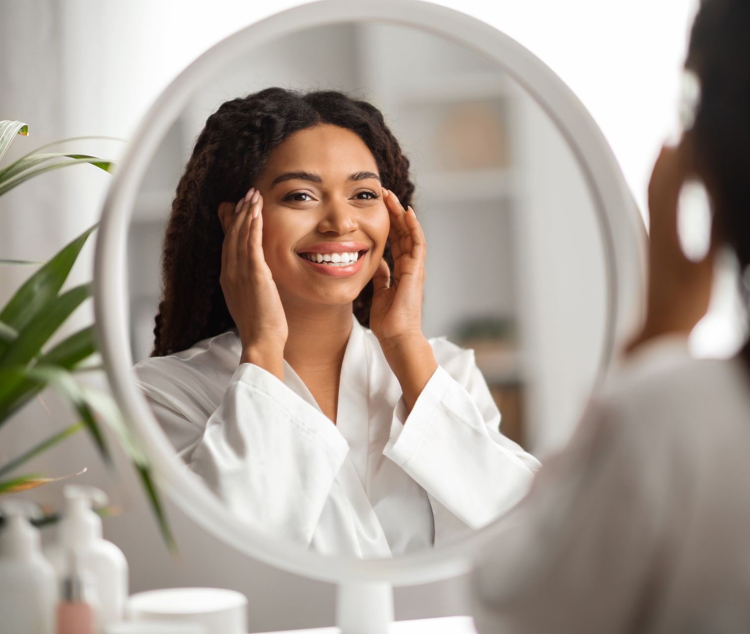 A woman is looking at her face in a mirror.
