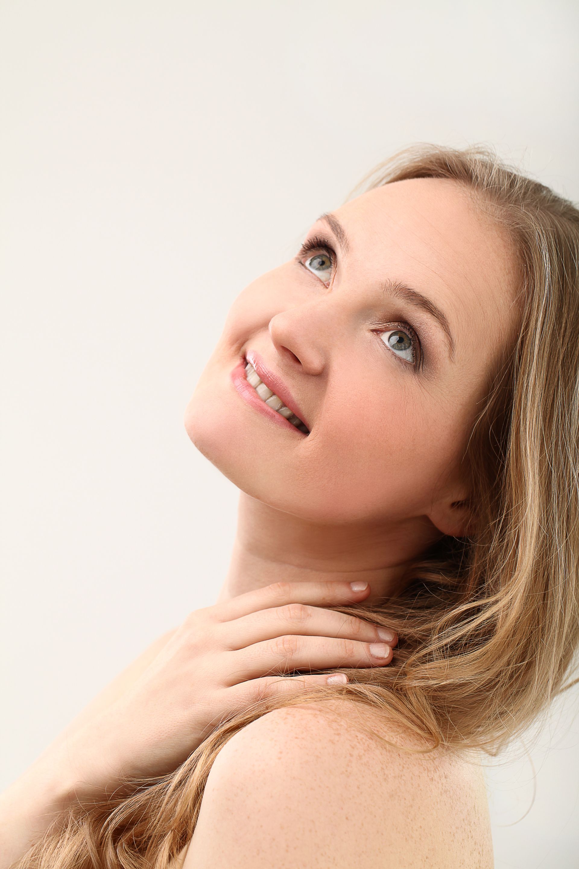 A woman with long blonde hair is smiling and looking up.