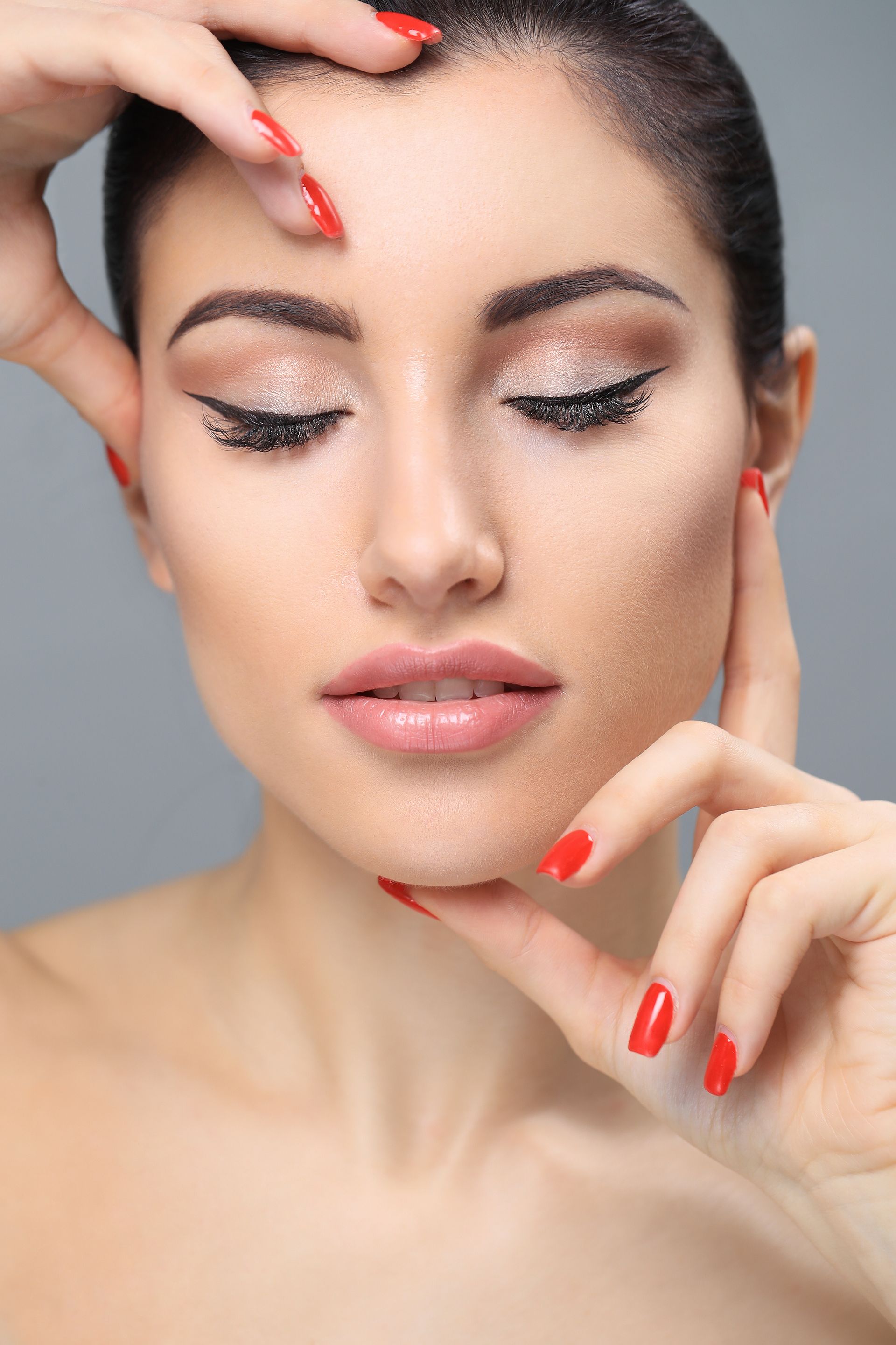 A close up of a woman 's face with red nails.