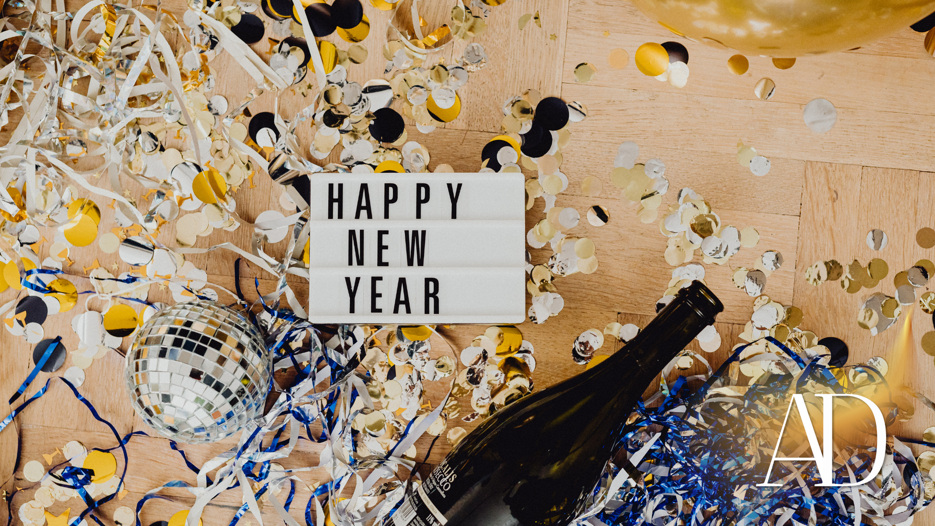 Happy New Year sign amid gold, black, and white confetti and party decorations