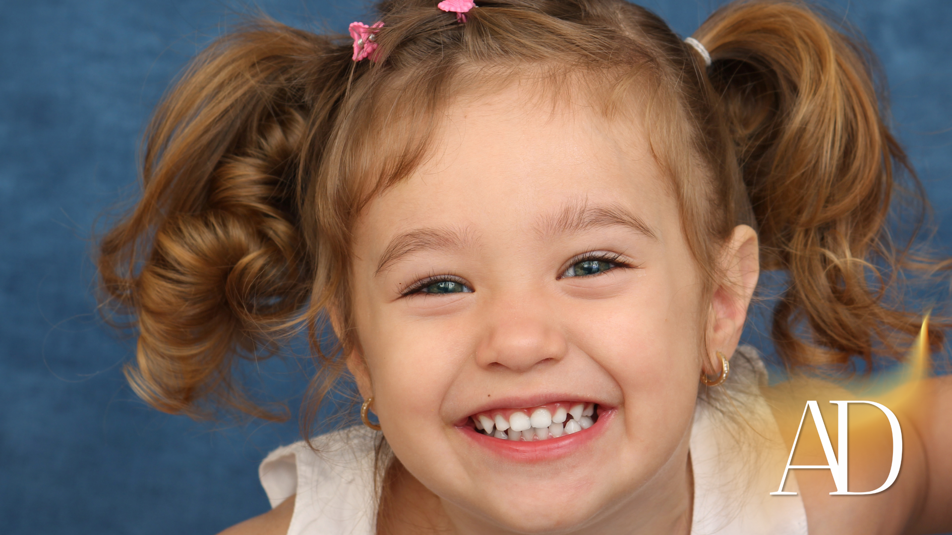 Smiling child with pigtails against a blue background