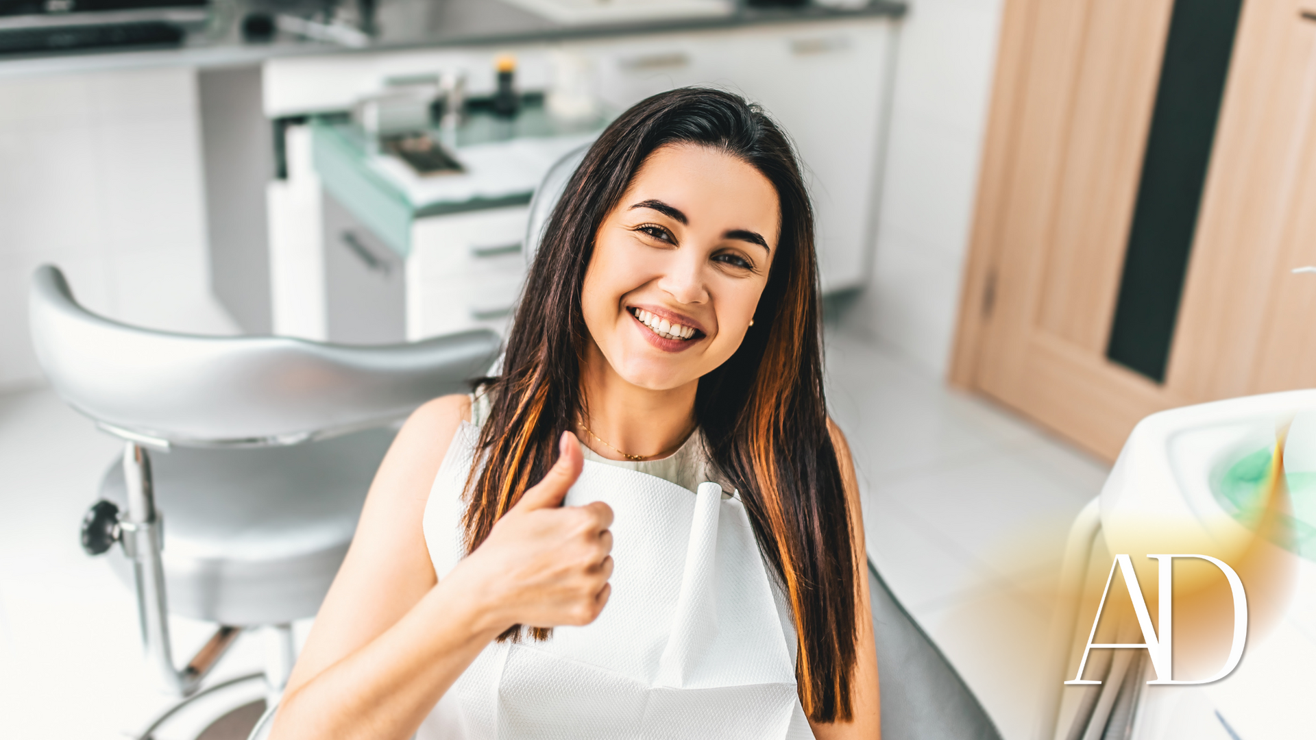 Smiling woman giving a thumbs-up in a bright dental clinic chair