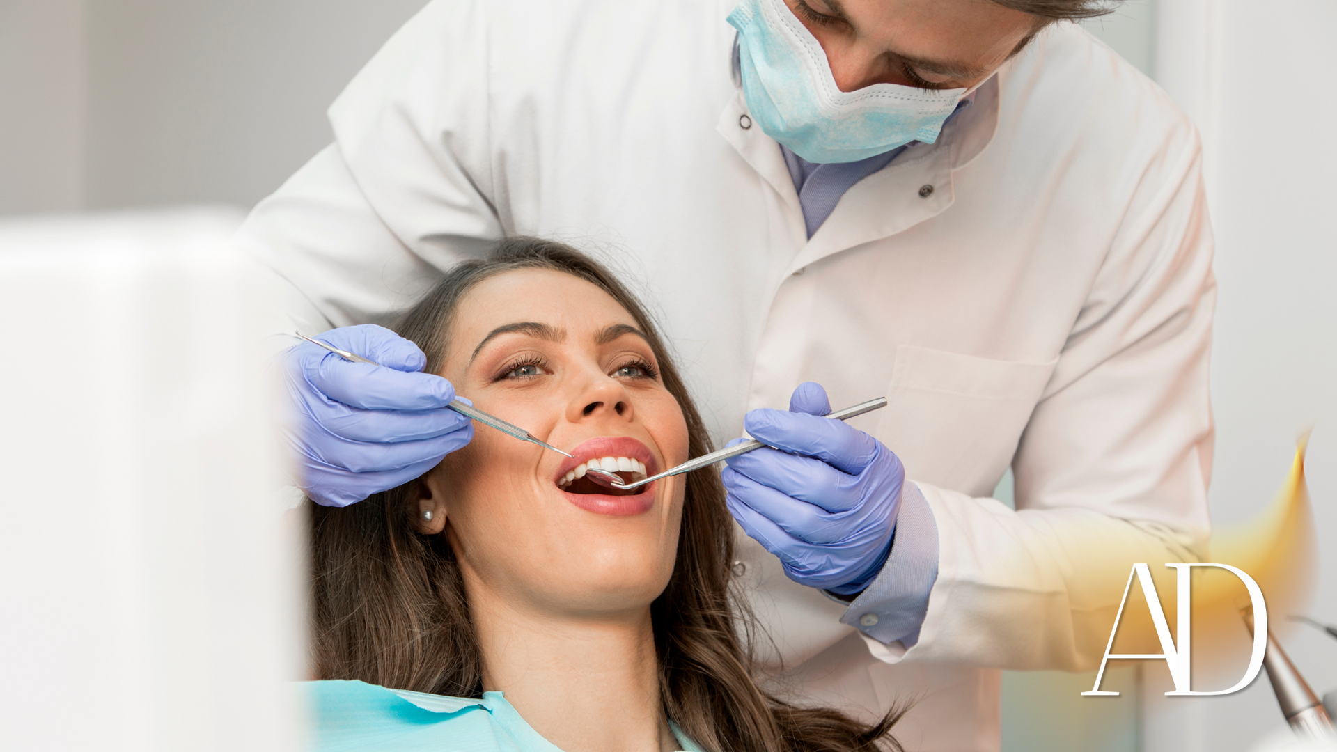 Dentist examining a smiling patient’s teeth with a mirror and probe in a clinic
