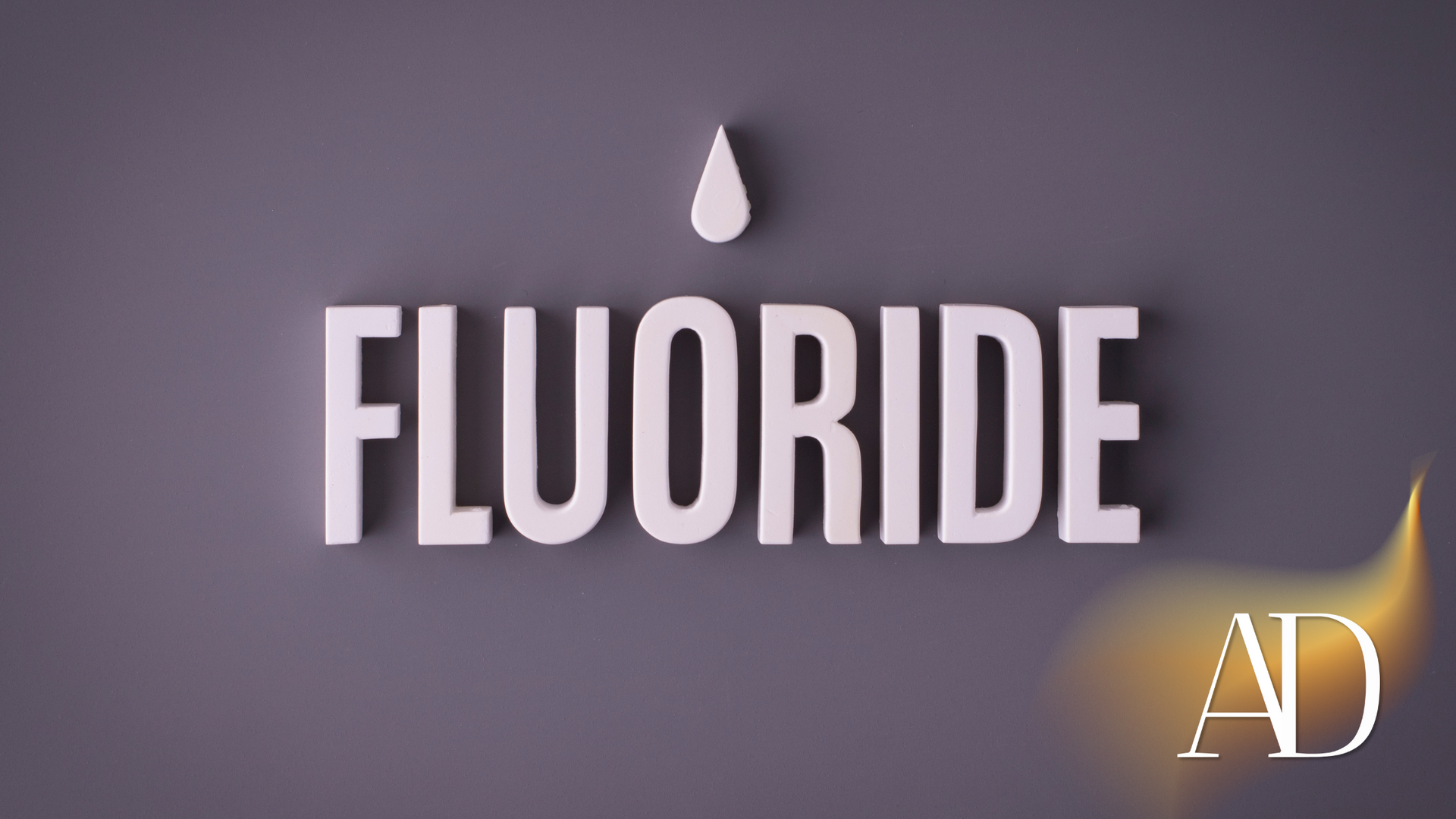 White “FLUORIDE” text and droplet on a gray background with a small AD mark in the lower right.