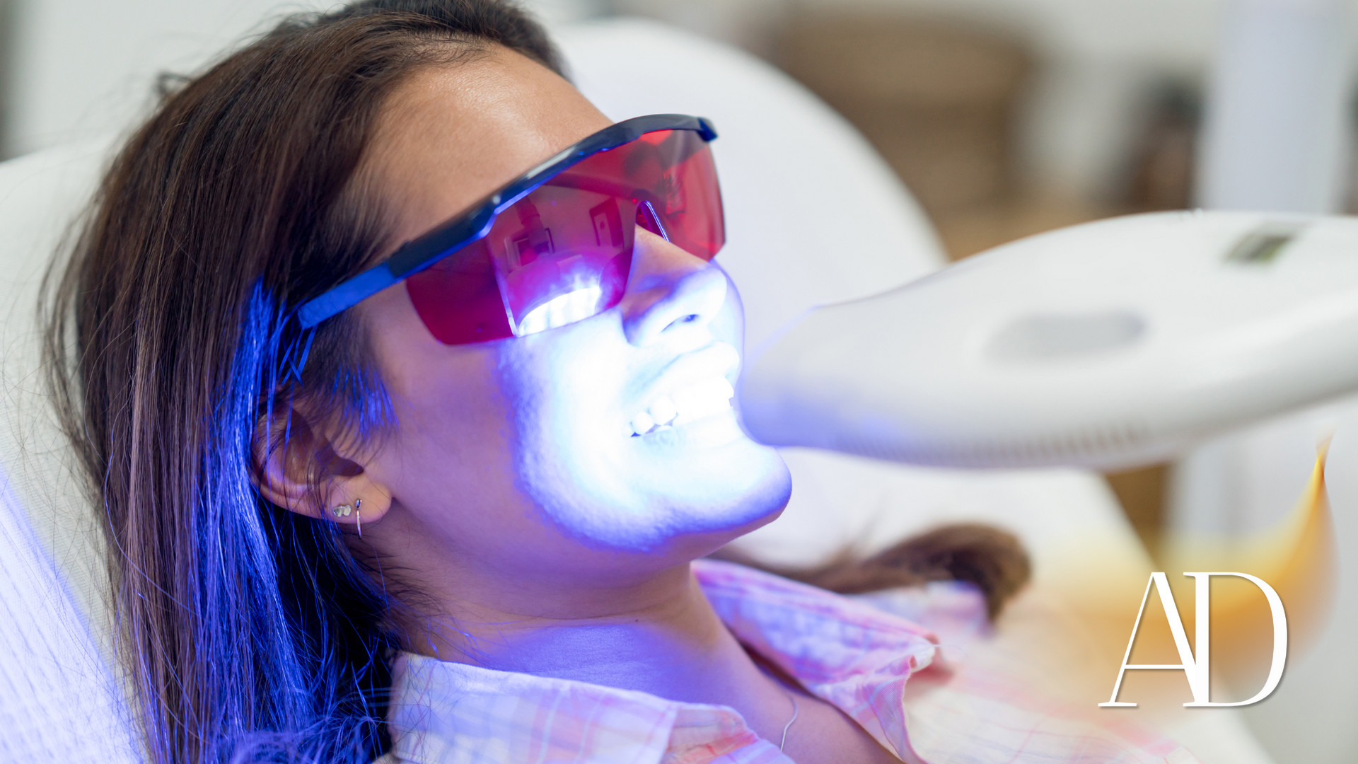 Woman receiving blue light treatment while reclining with protective red goggles