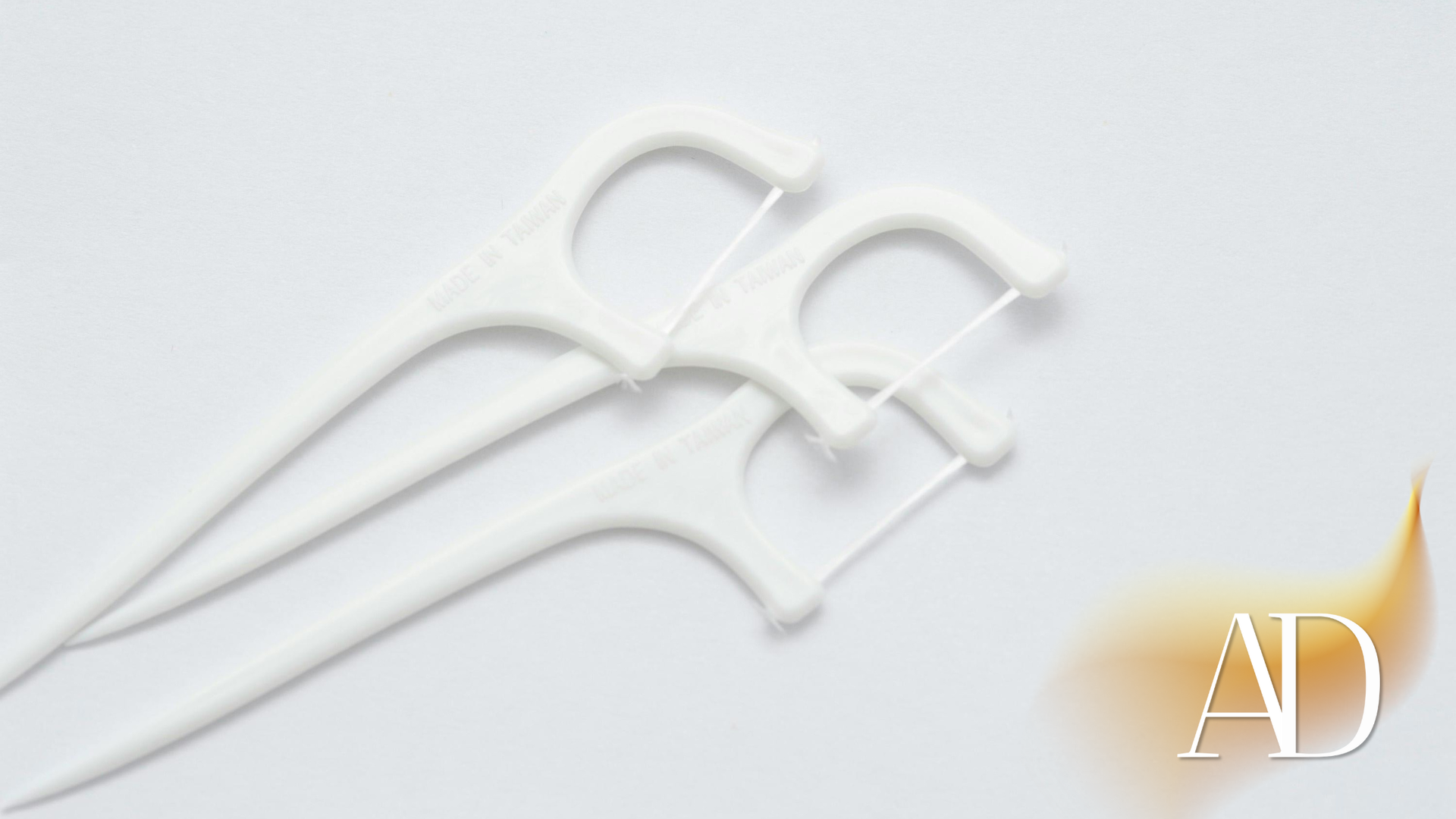 Three white crochet hooks on a light gray surface with an “AD” watermark in the corner