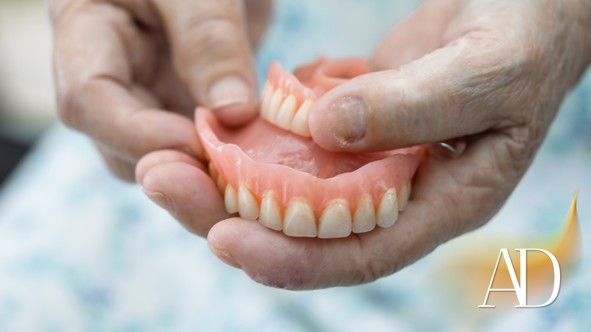 Hands holding a pink set of dentures outdoors