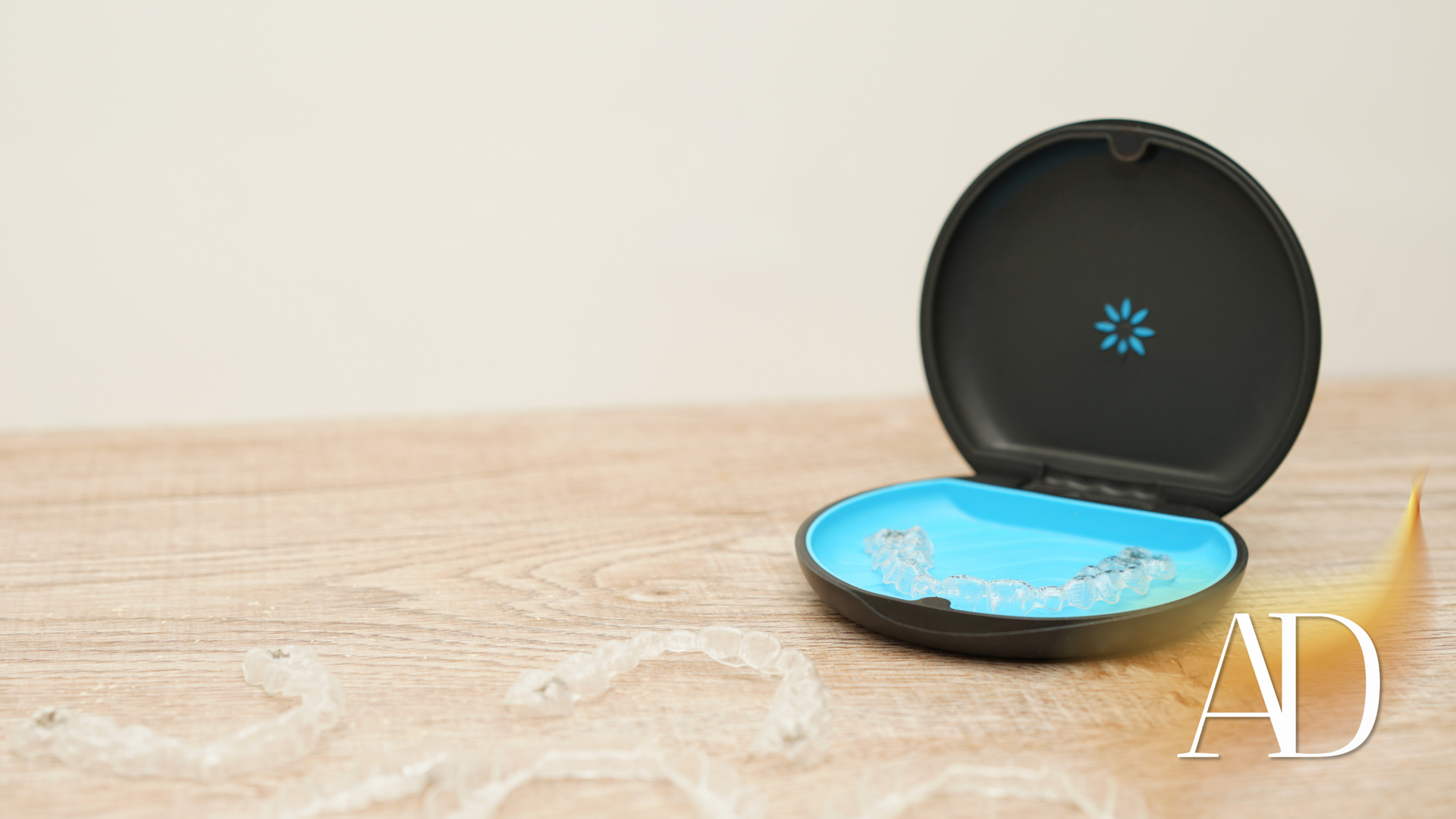 Open compact black and blue case on a wooden tabletop, with an “AD” watermark.