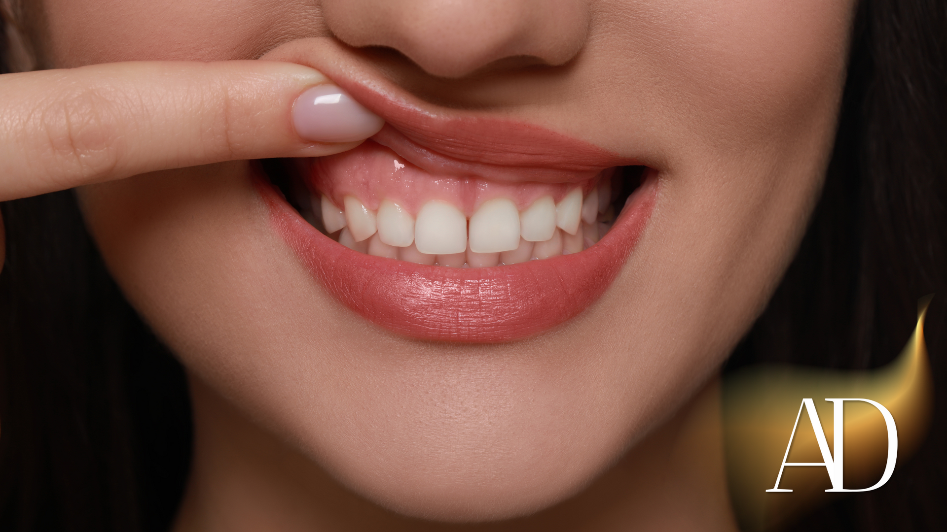 Close-up of smiling lips and teeth being lifted by a finger, with an “AD” watermark.