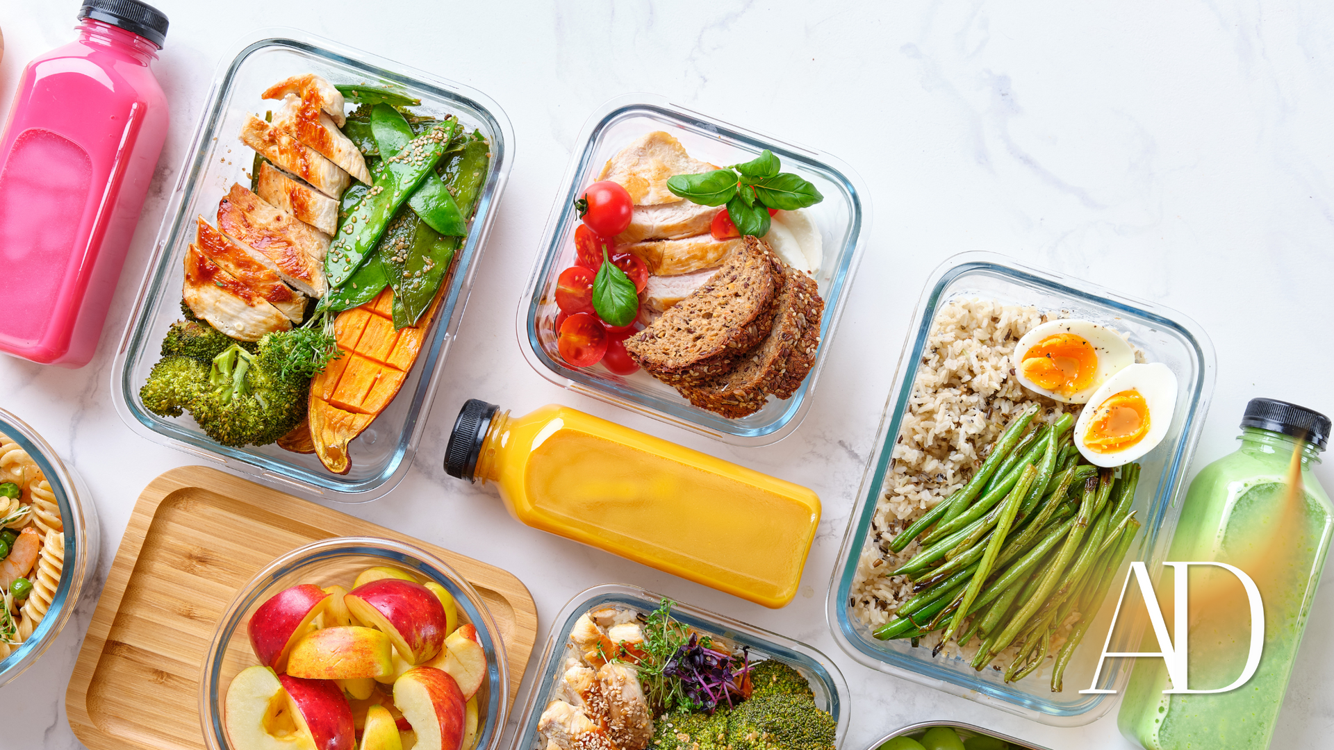 Assorted meal-prep containers with salmon, steak, green beans, and fruit on a white surface