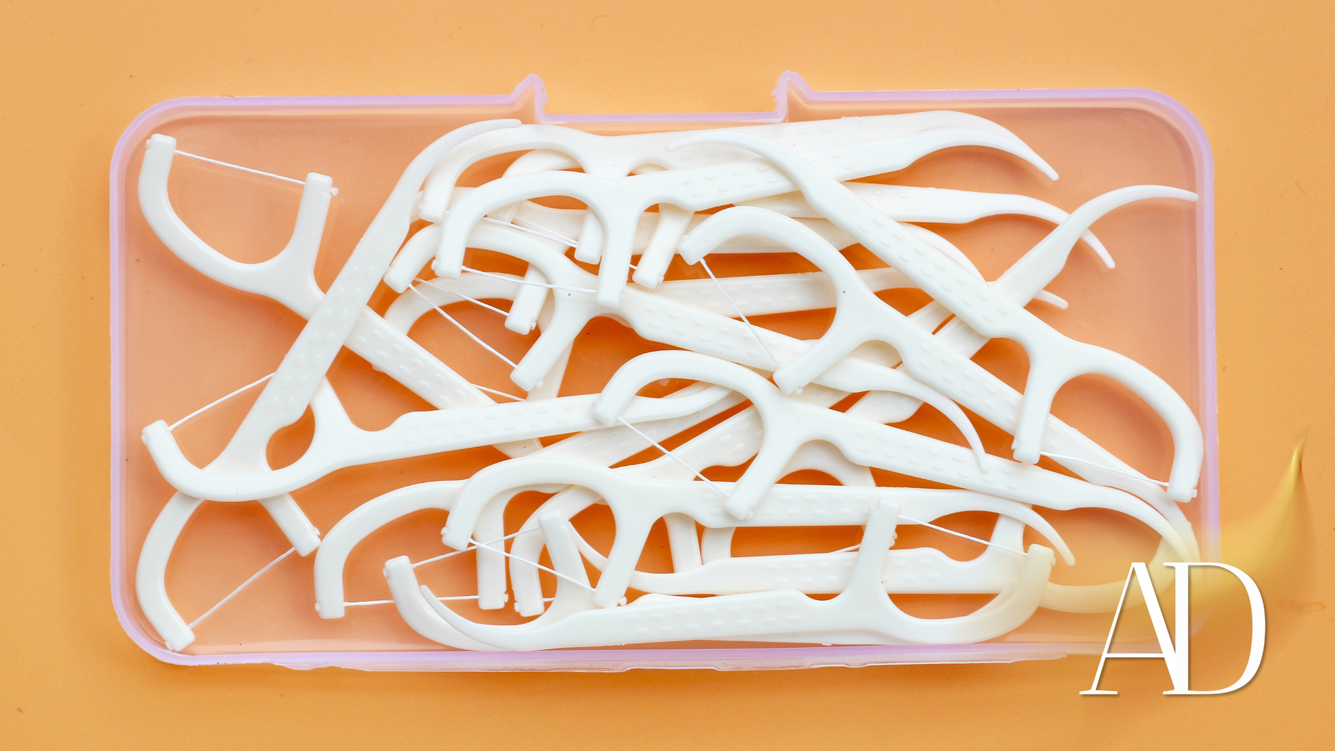 Pile of white plastic hangers in a pink tray on an orange background