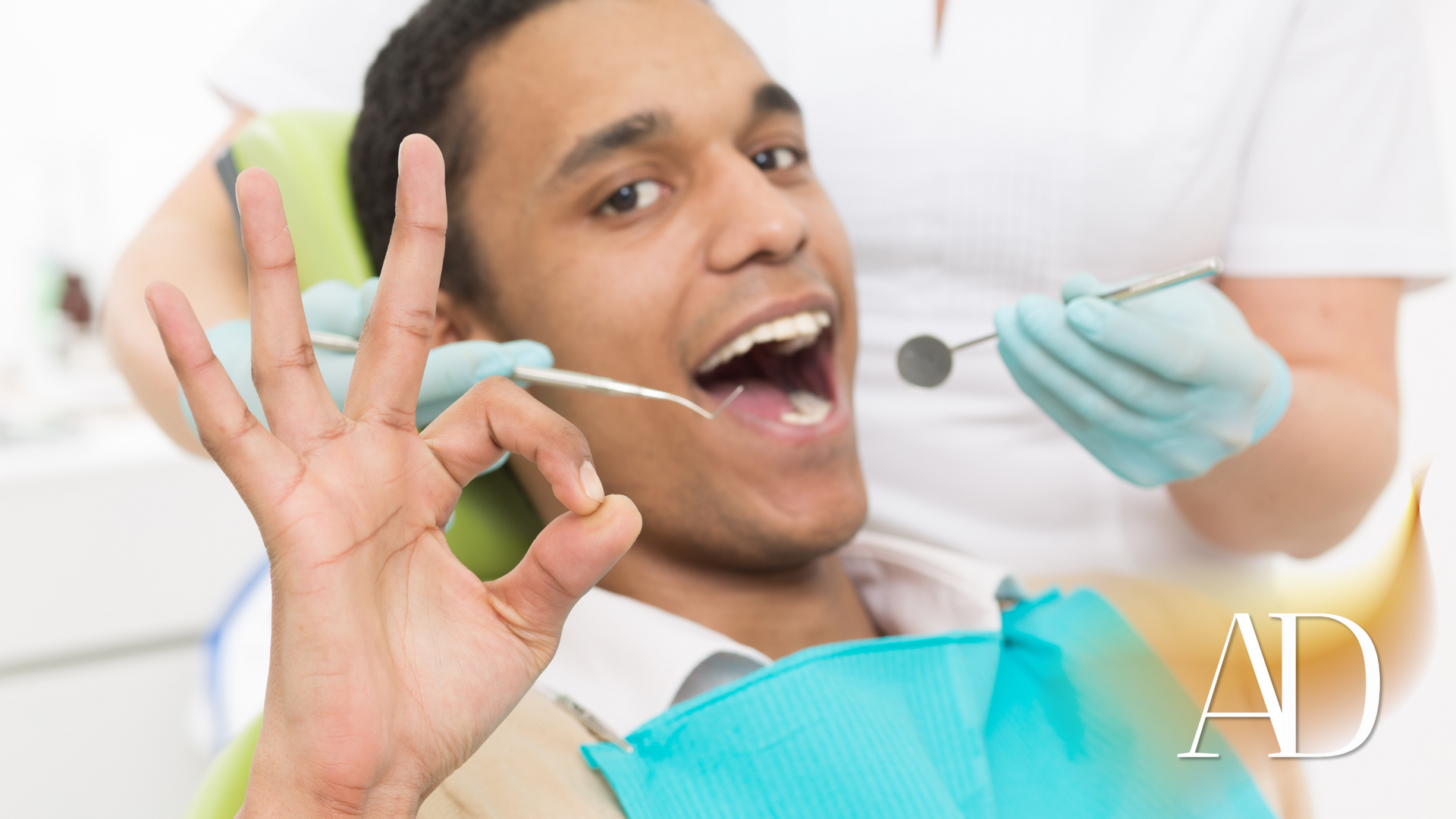 Smiling dental patient giving an OK sign while dentist holds a mirror in a bright clinic