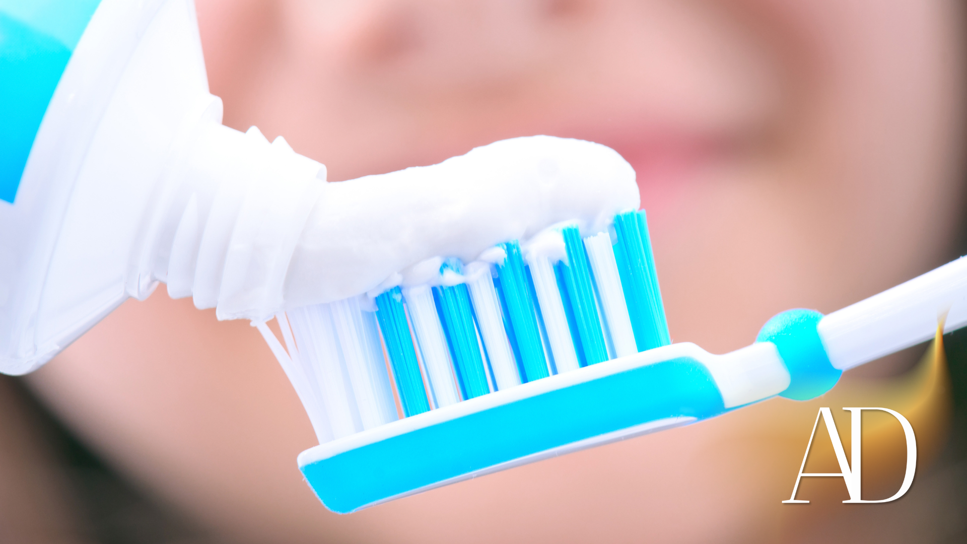 Toothbrush with blue bristles near a smiling mouth, with an 