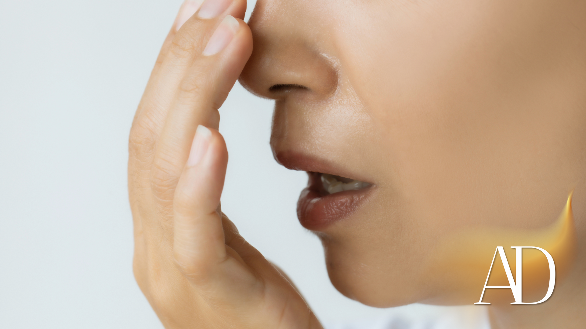 Close-up of a person pinching their nose and touching their upper lip with a finger, suggesting a smell or bad odor
