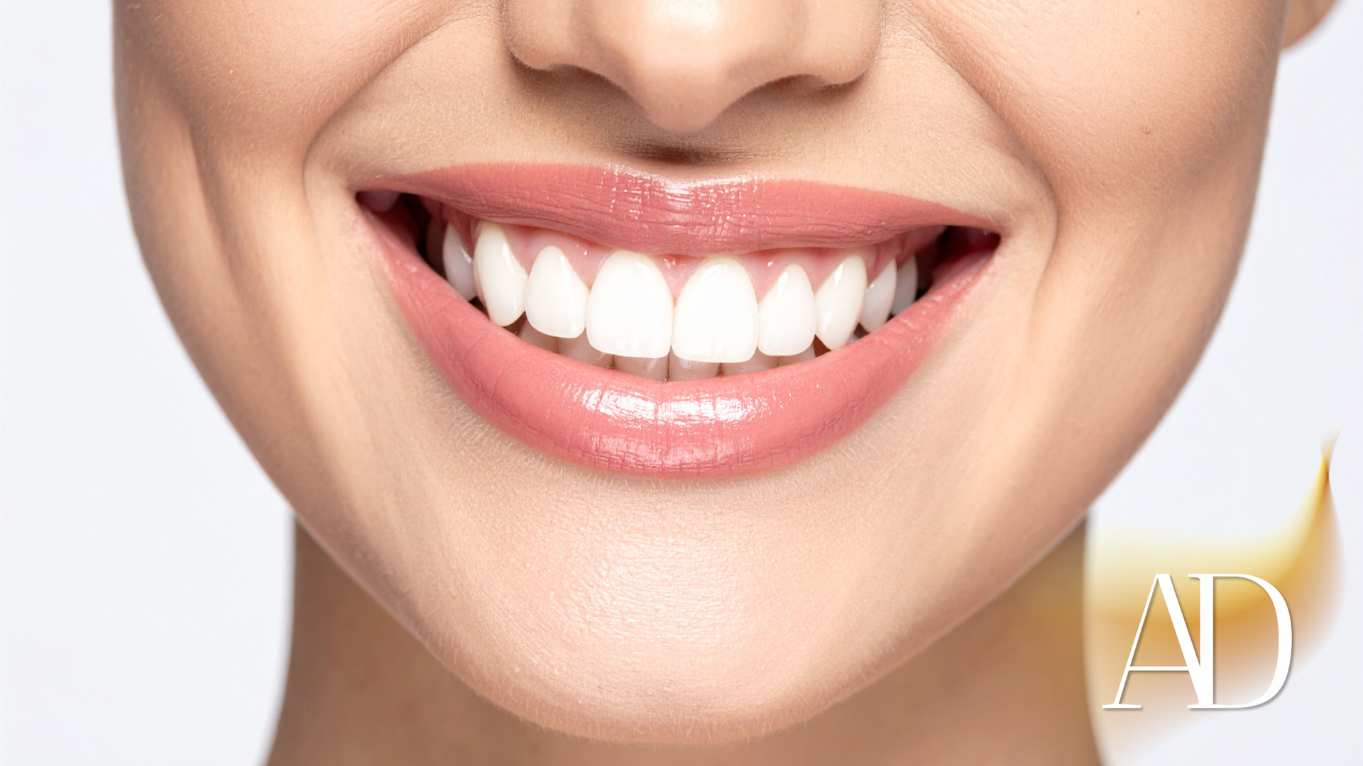 Close-up of a smiling mouth with bright white teeth and glossy pink lips