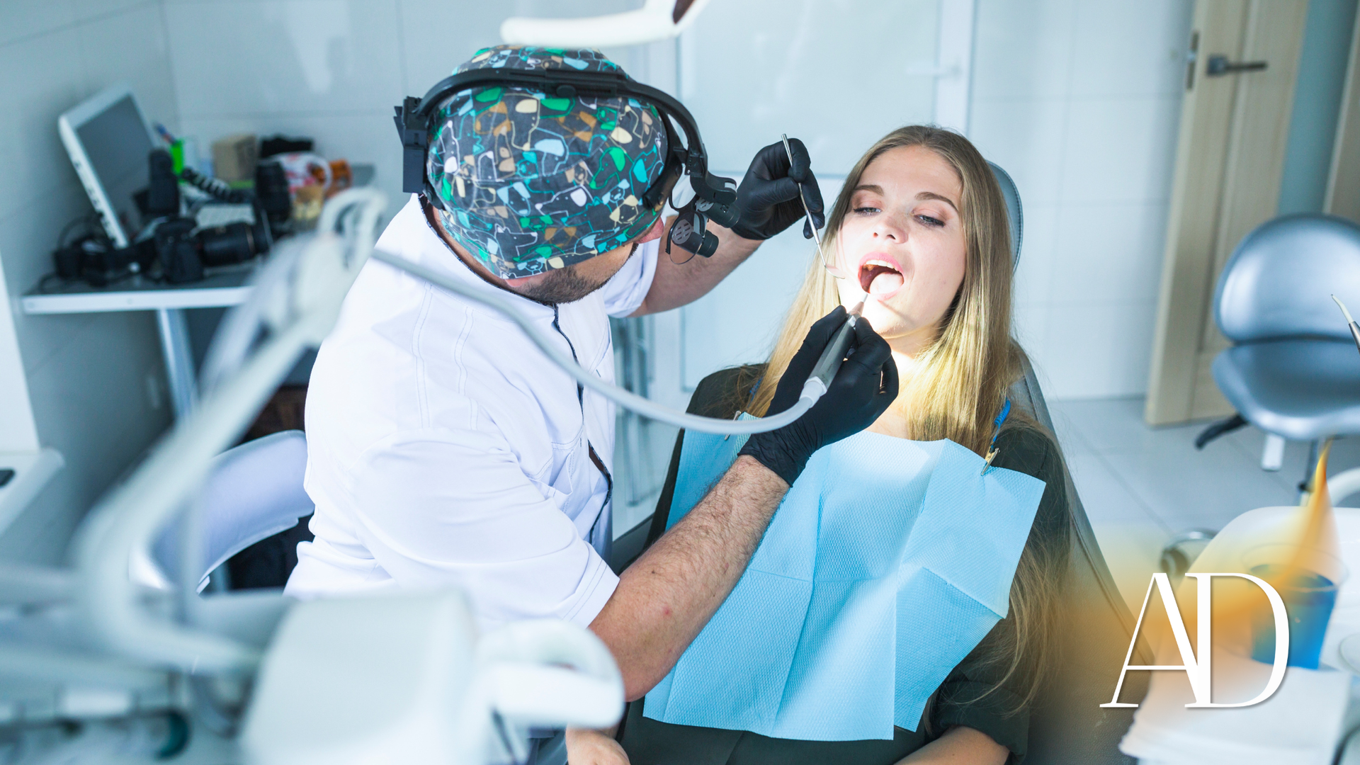 Dentist examining a patient in a bright dental office while she sits in a chair with mouth open