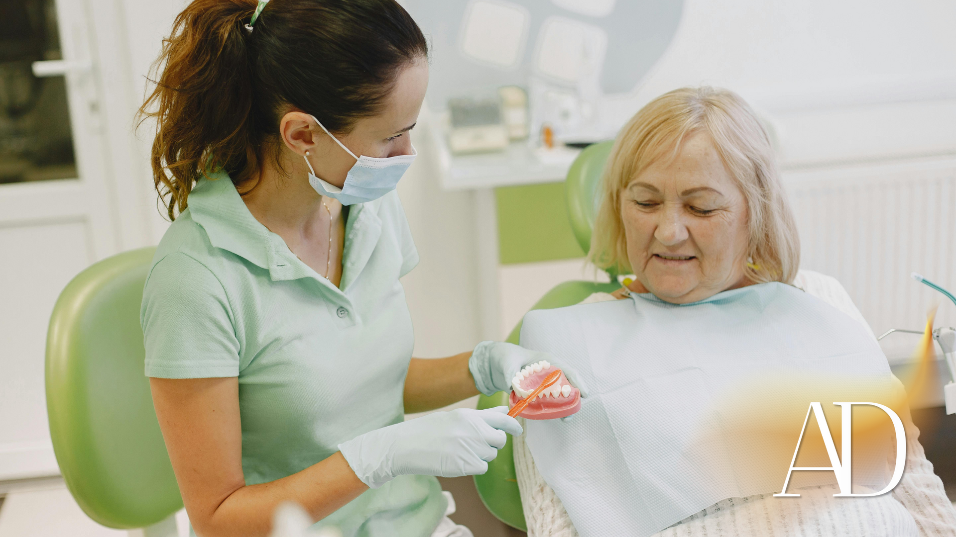 Caregiver showing a dental model to a seated patient in a bright clinic room