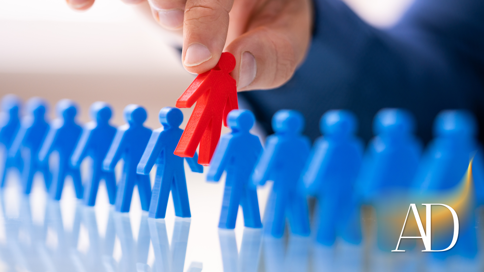 Hand placing a red figure among blue figures in a row of people-like tokens