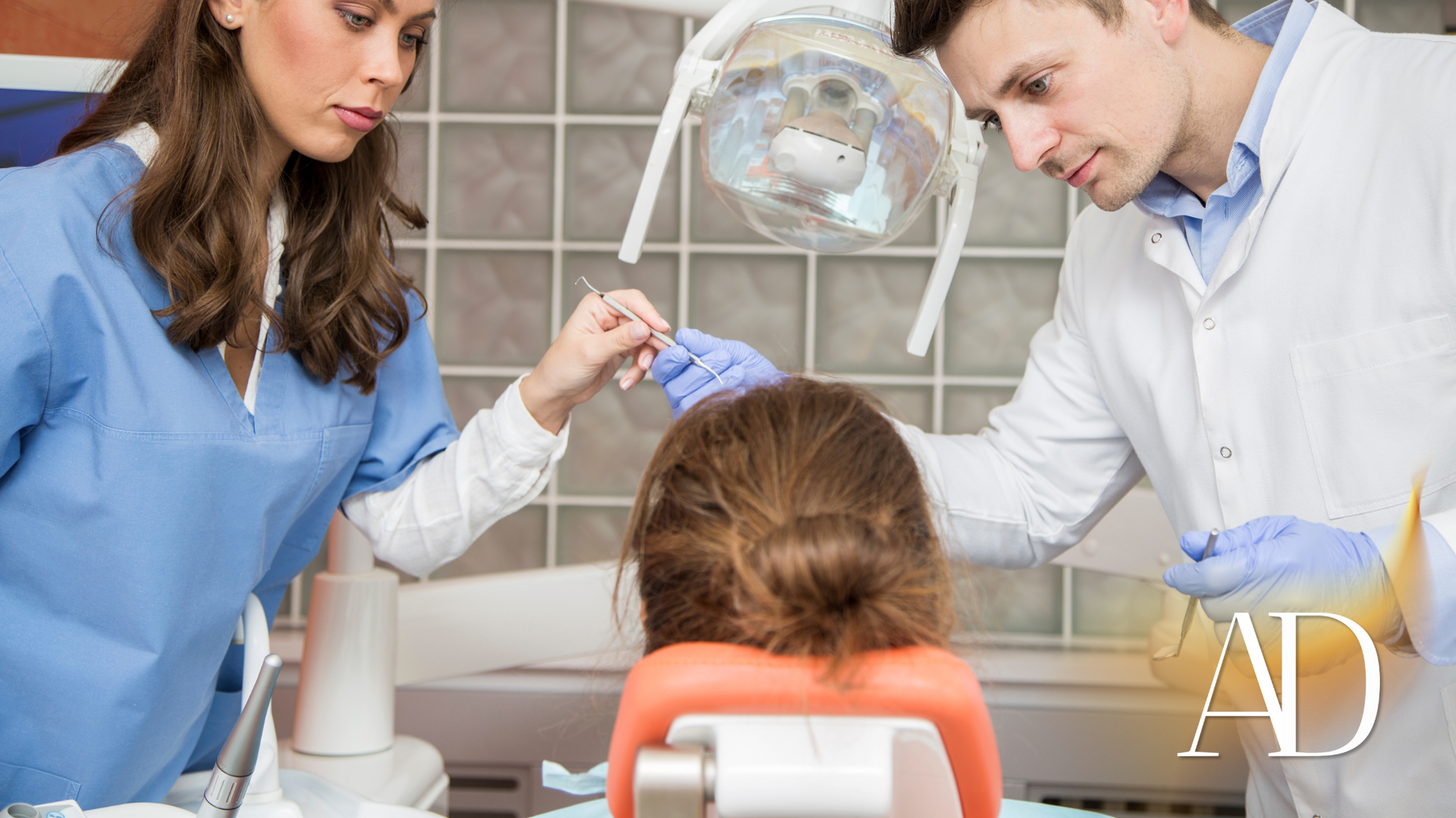 Dentist and assistant examining a patient in a dental chair, focused on treatment.